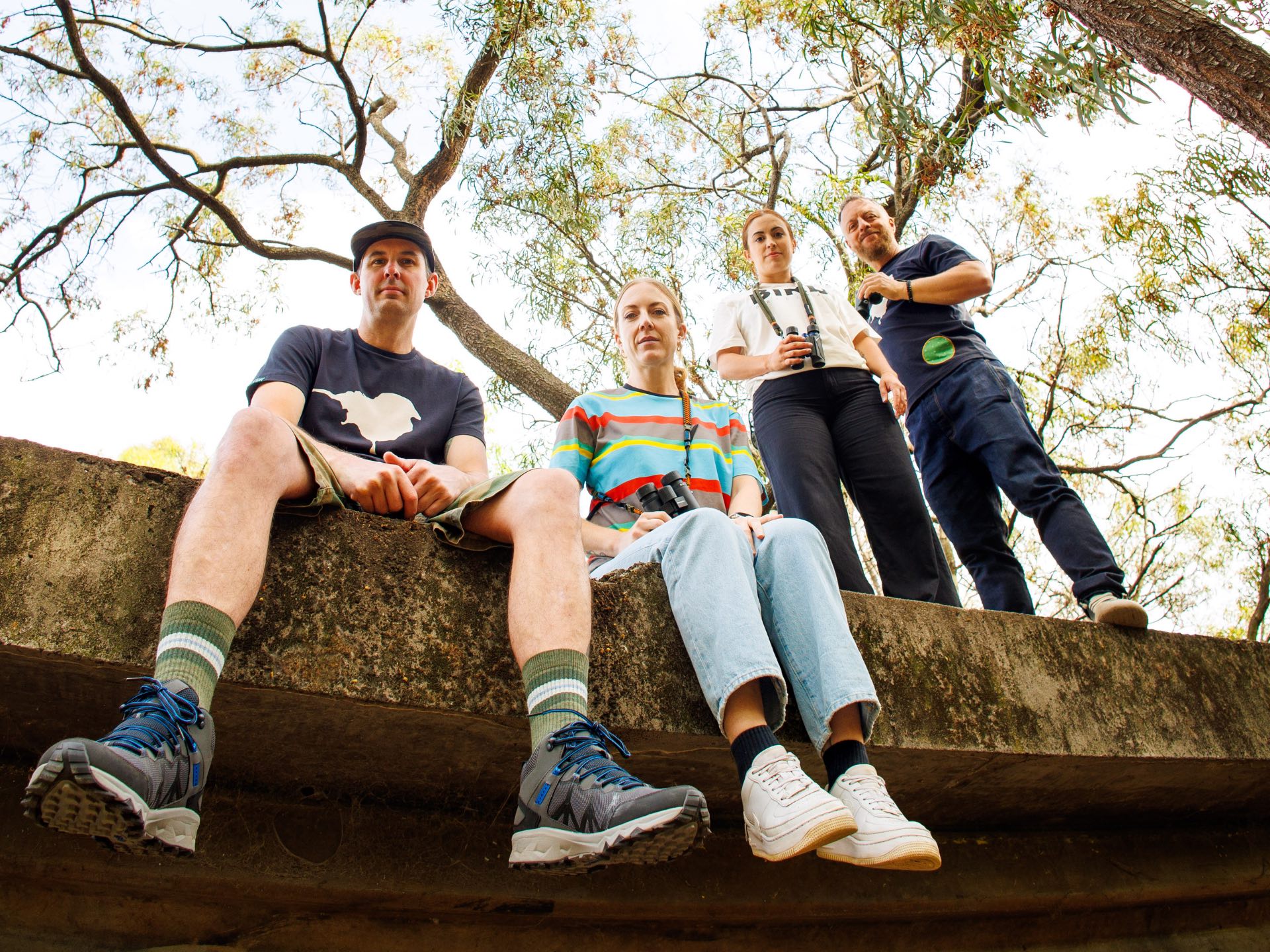 Image of Birders sitting on ledge out in nature birding. Showing the lyfer gear of bird gifts for birdlovers.