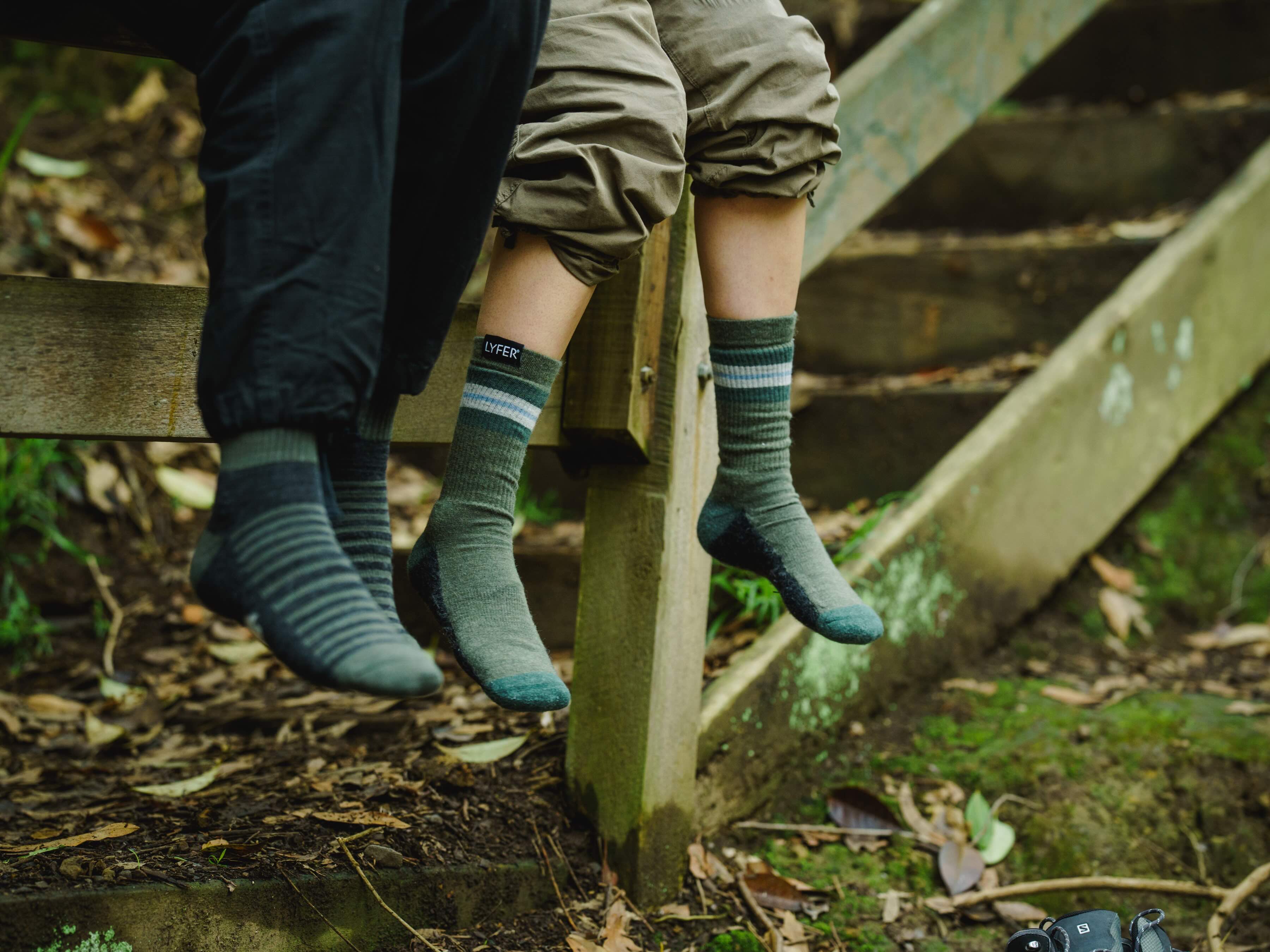 Lyfer outdoor socks worn by model sitting on fence