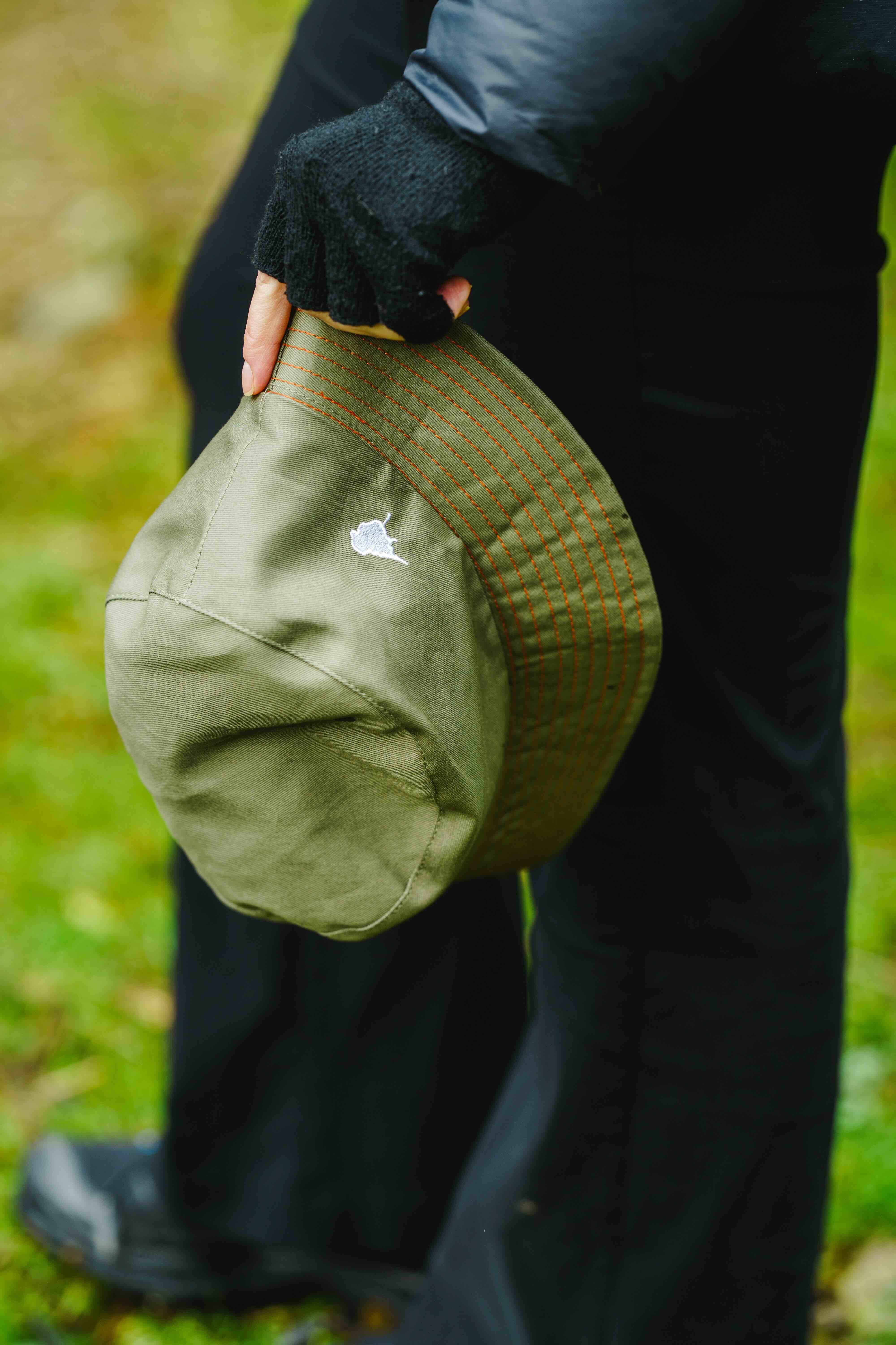 Model holding the lyfer birdmark bucket hat our in nature birding.