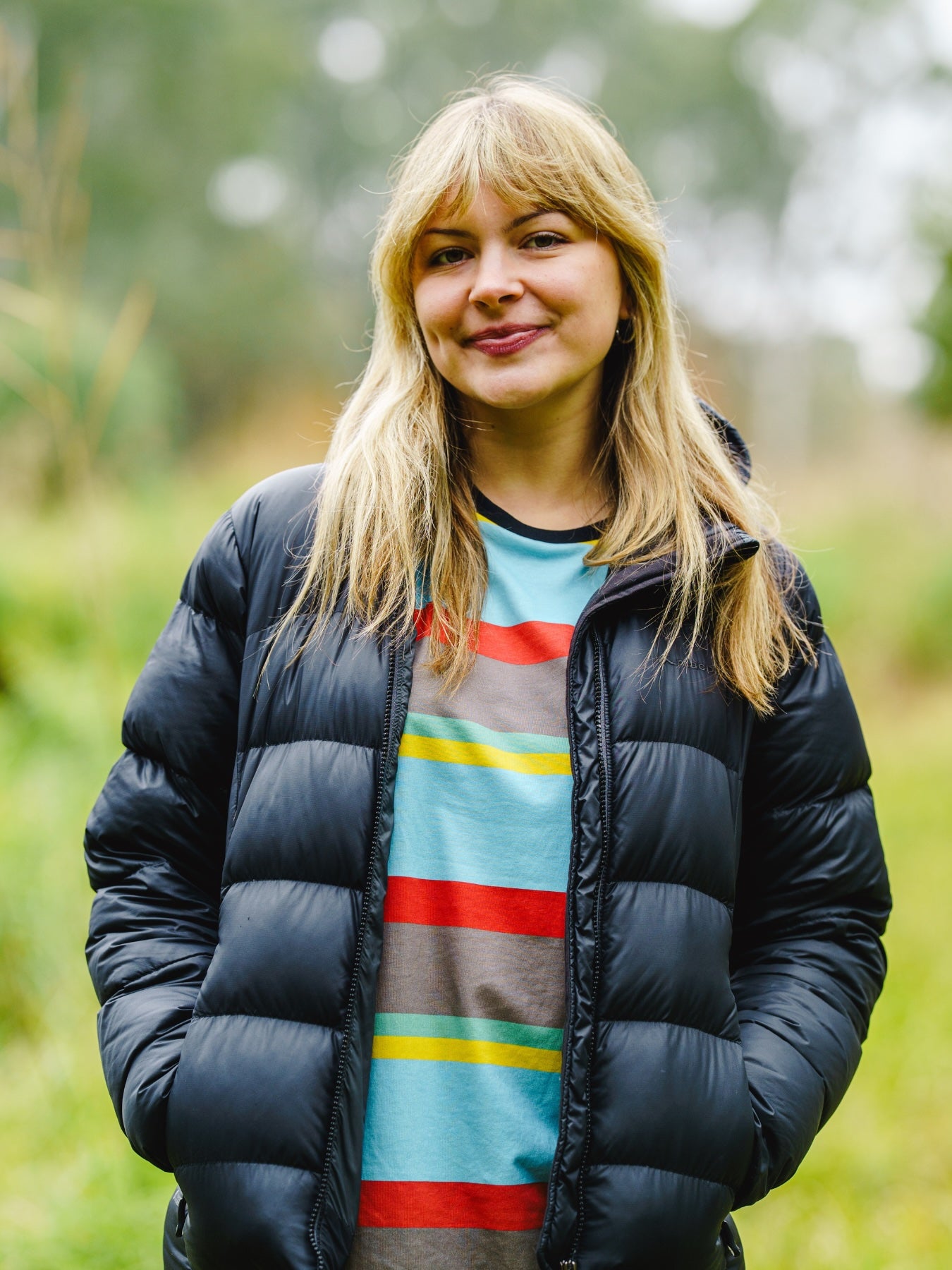 Model wearing the Endangered range tshirt of the golden-shouldered parrot under a winter jacket, showing the colours of the bird.