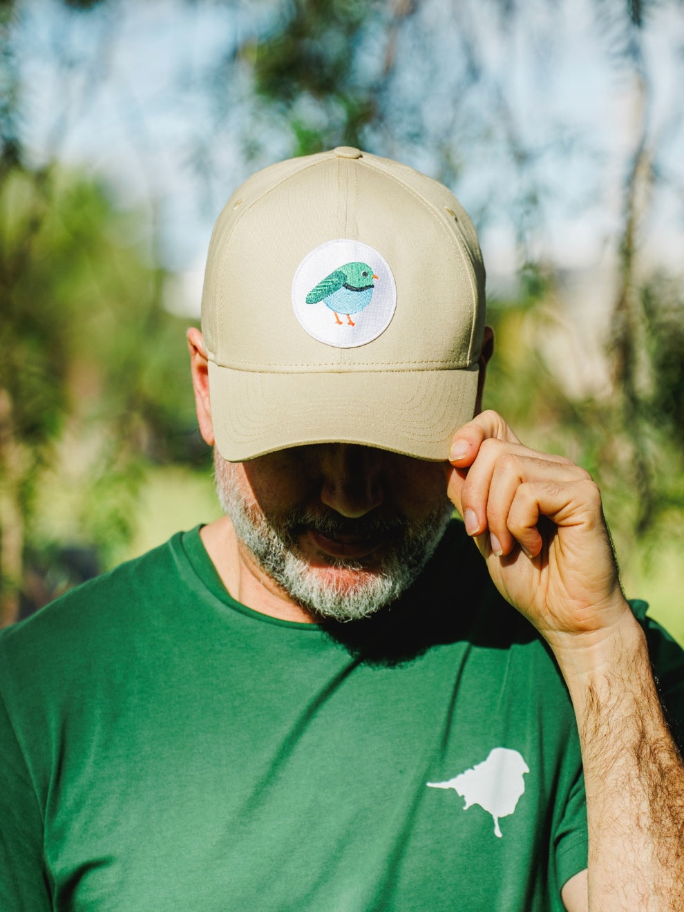 Model wearing the LYFER Patch Cap - Male Bird holding the rim