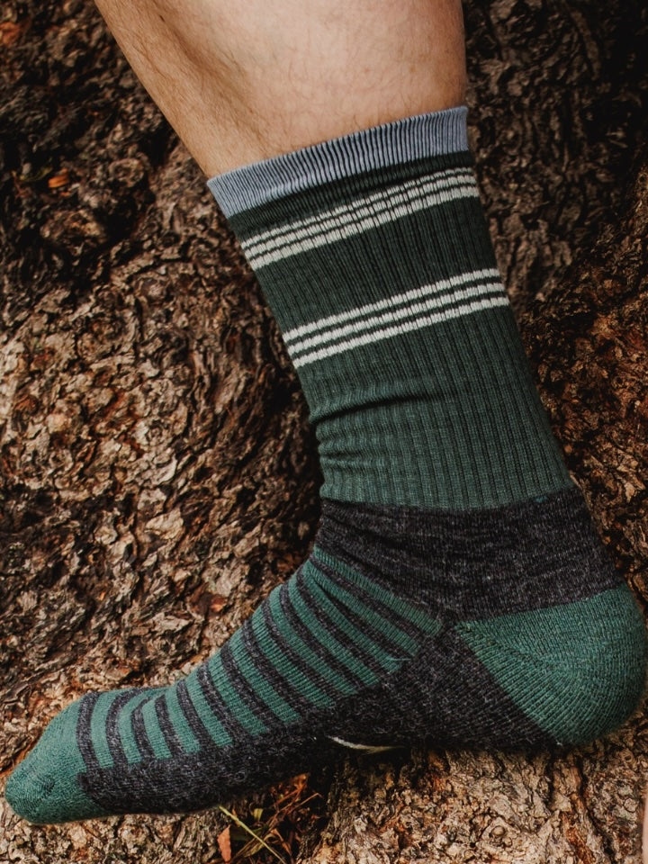 Green and black striped socks worn on a textured surface