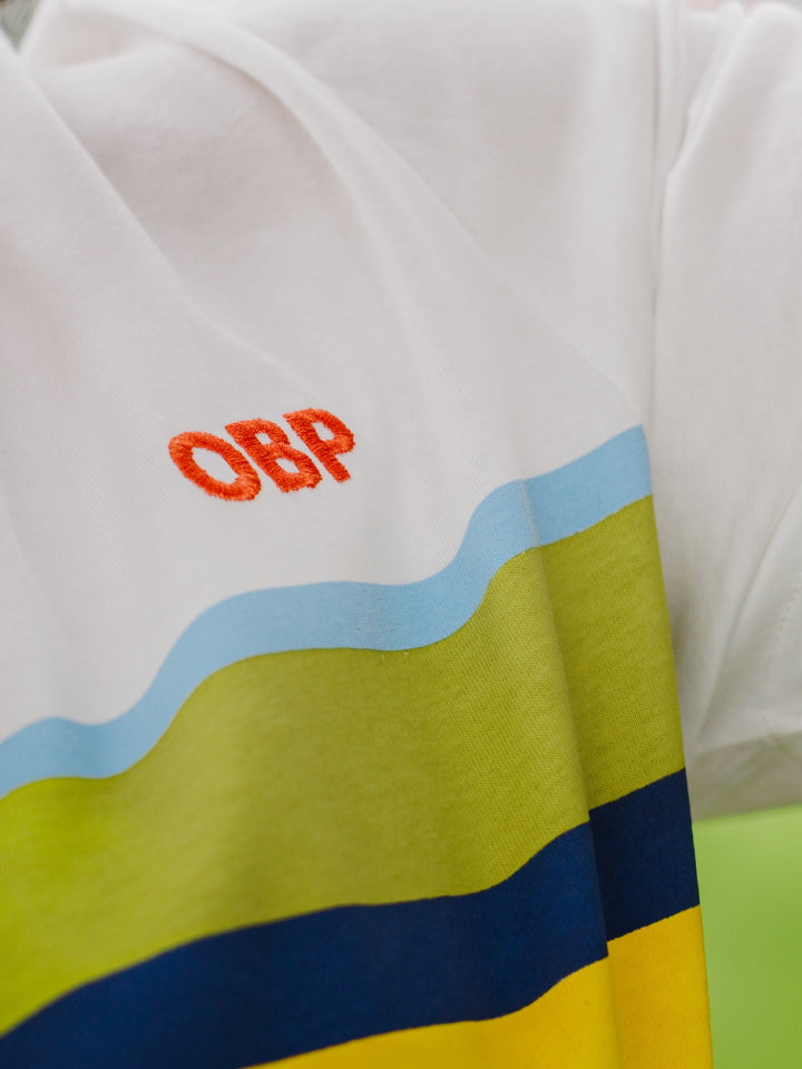 Close-up of a OBP Endangered Range Tee in white shirt with colorful stripes and 'CBP' logo.