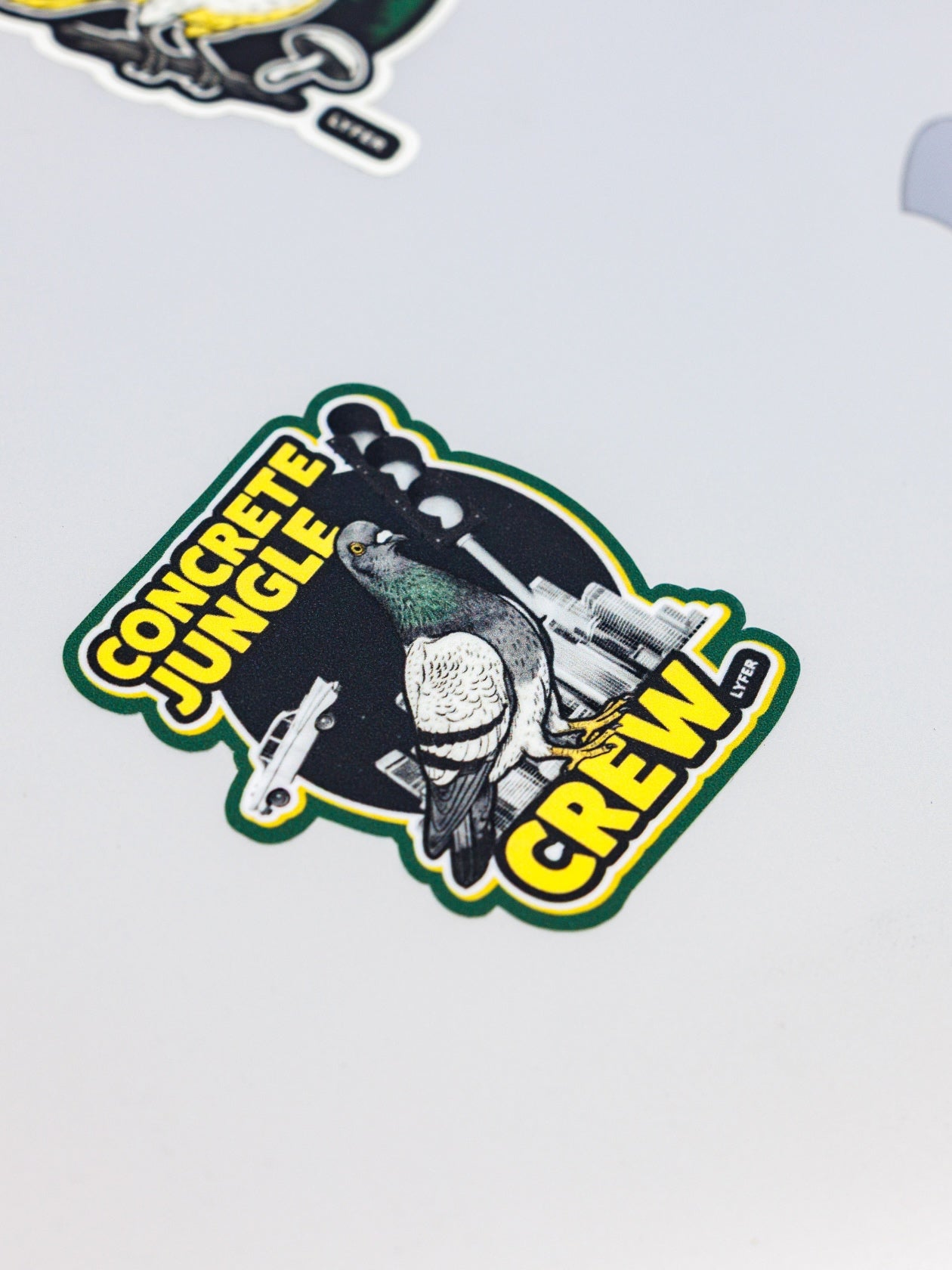 Sticker with a pigeon and text 'Concrete Jungle Crew' on a light gray background