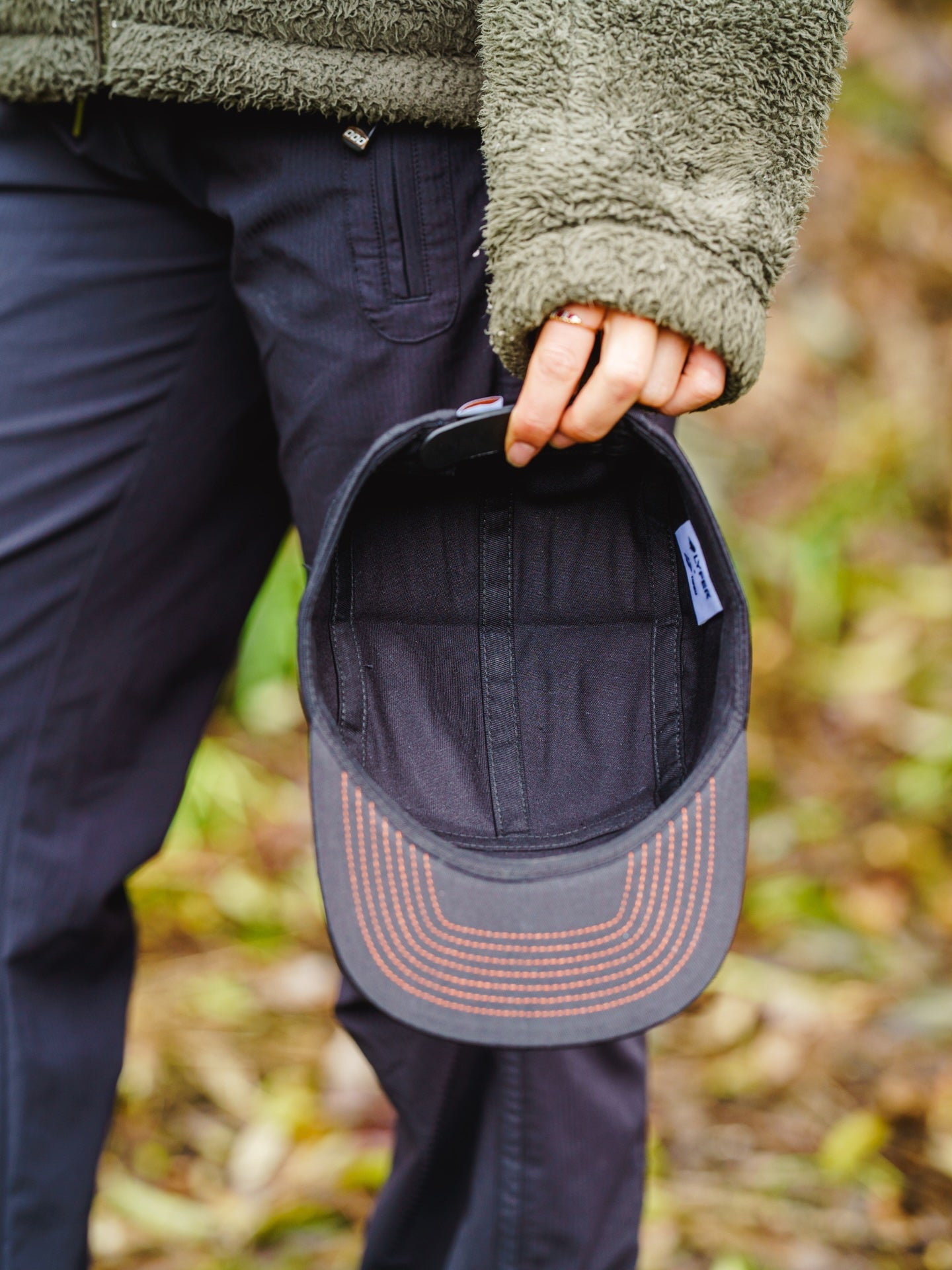 Model holding the Lyfer 5 panel cap showing the internal details, while out in nature.