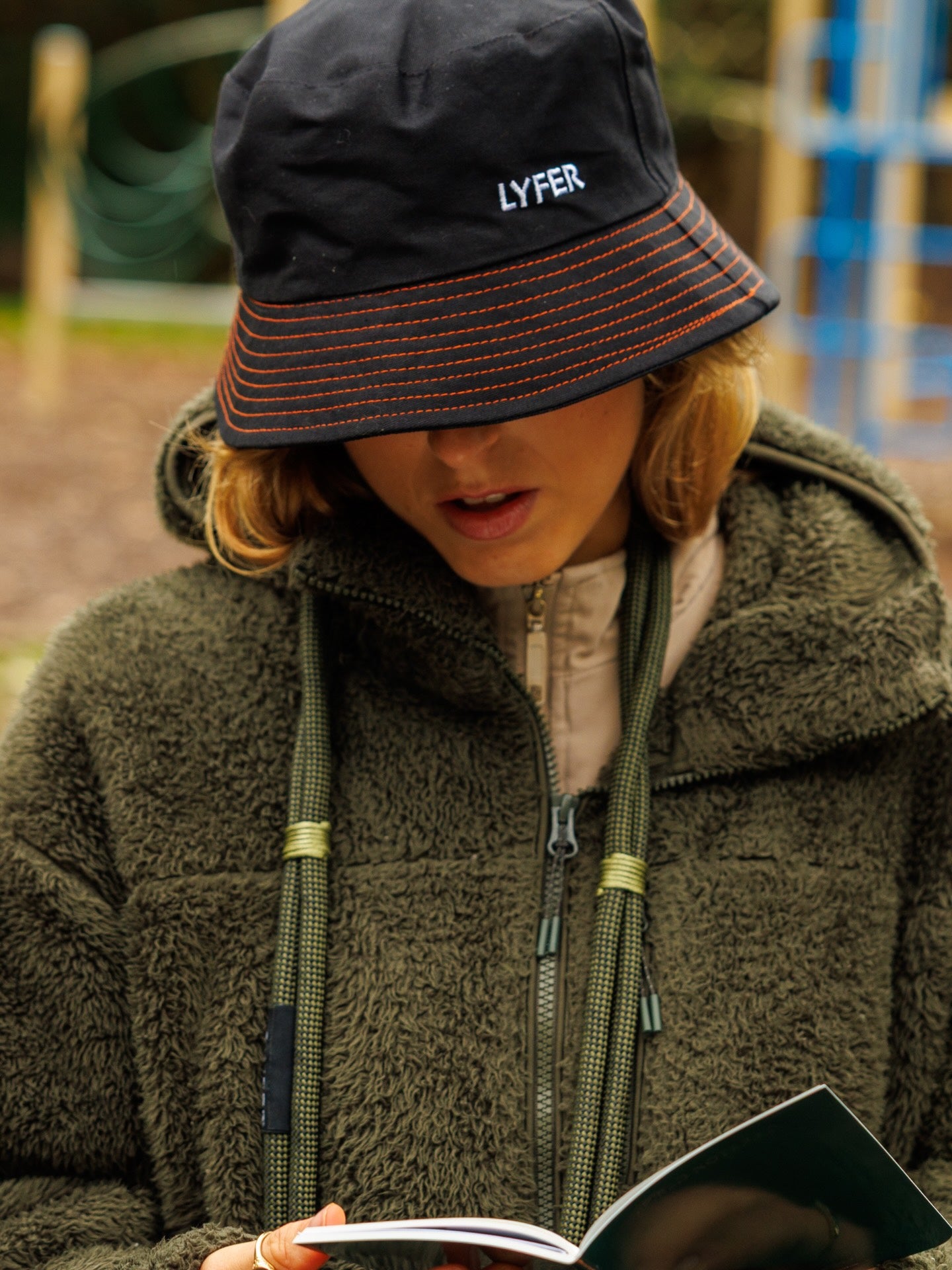 Lyfer Brand Bucket Hat in Black worn by female out in nature, while birdwatching.