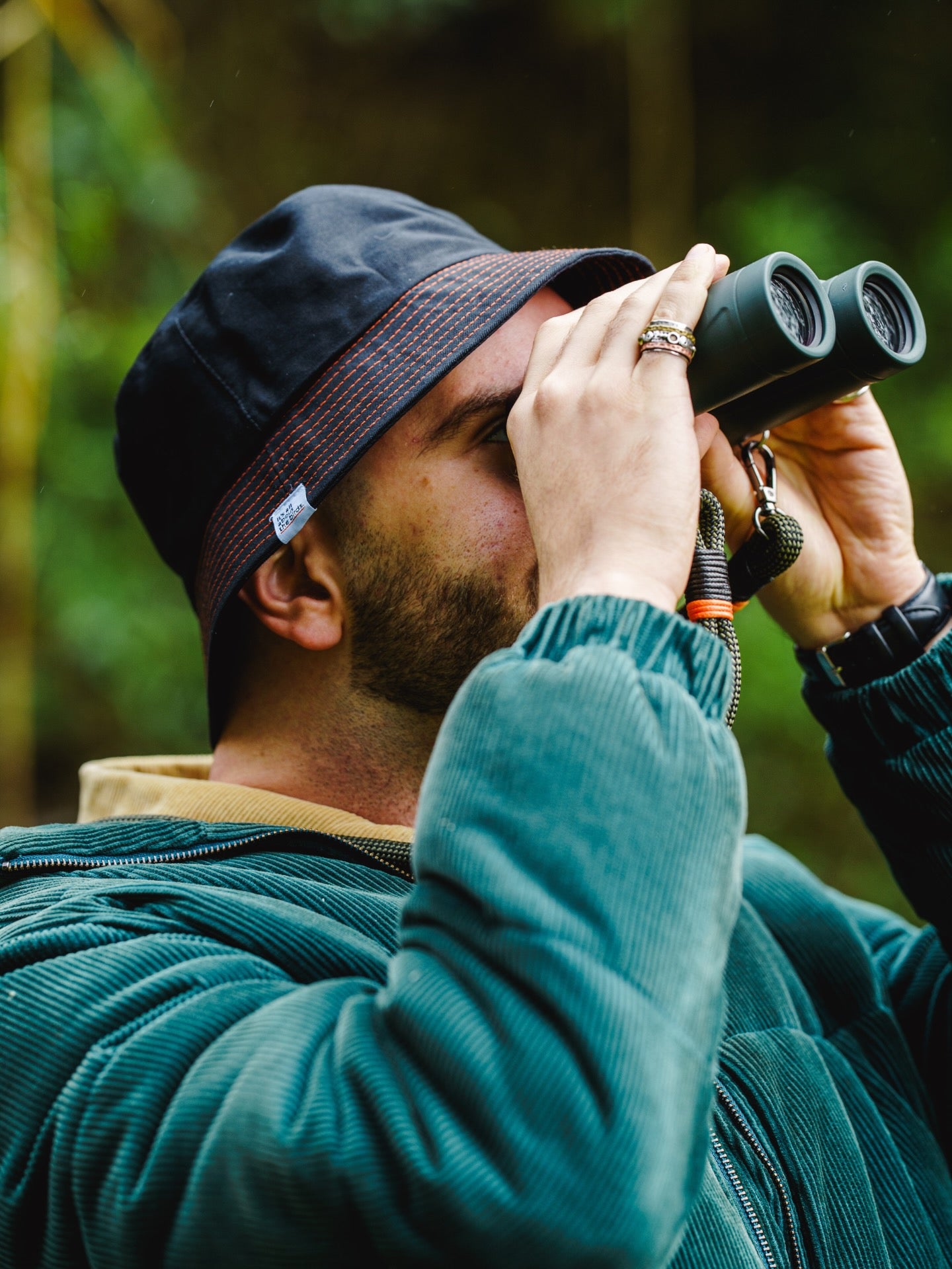 Lyfer Brand Bucket Hat in Black worn by model out in nature, while birdwatching.