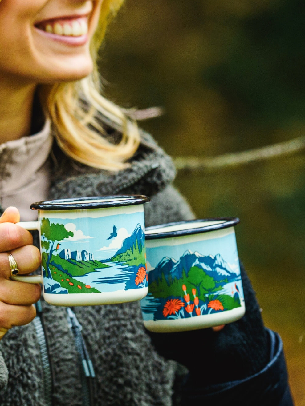 Image of two model holding the Lyfer enamel mugs with bird illustrations