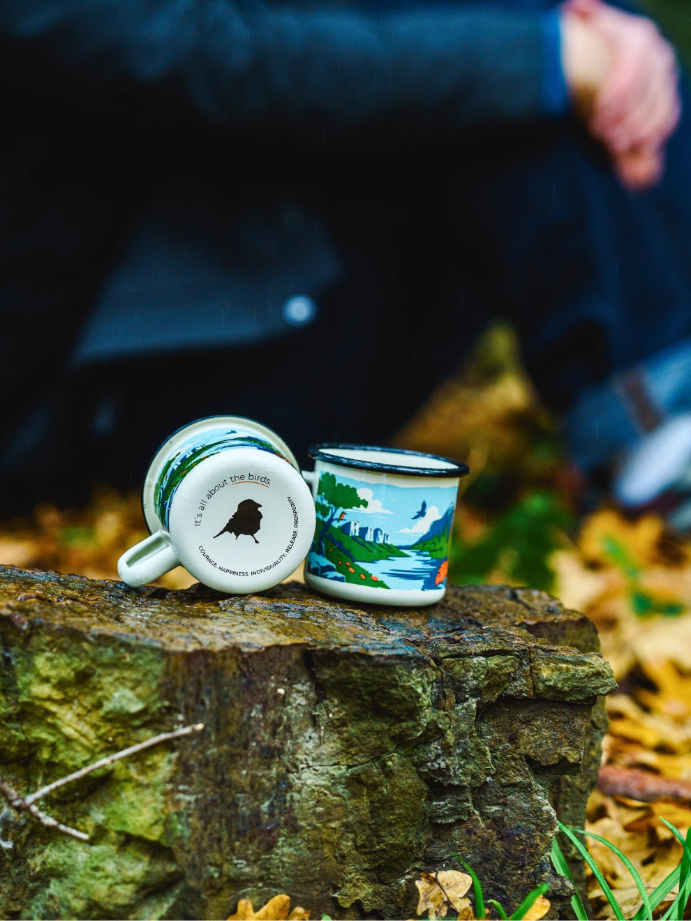 Image of Enamel Field Mug close up showing bird illustration and base birdmark logo with model in background
