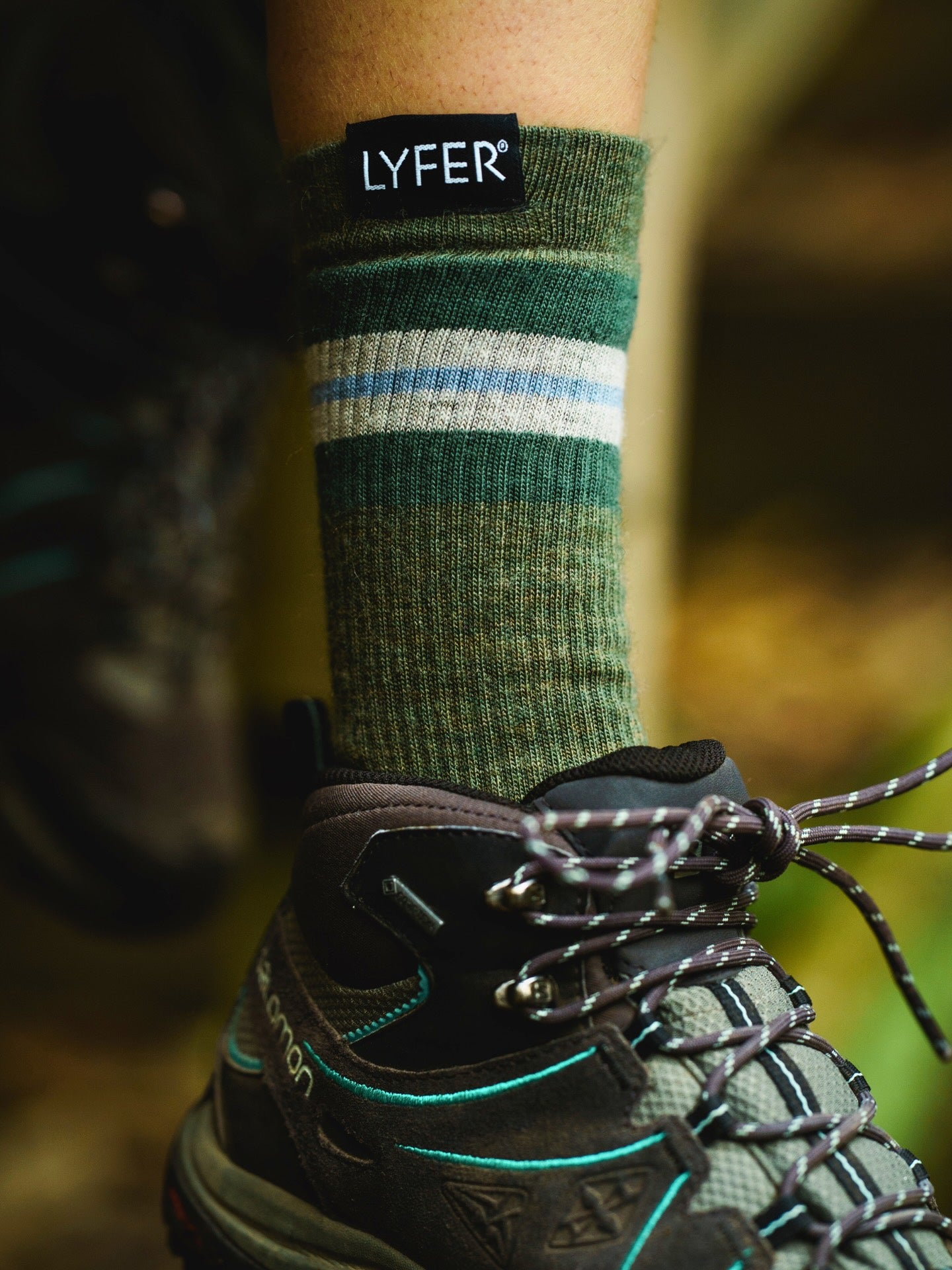 Lyfer Original Field Socks with with LYFER branding worn on a foot, blurred background.