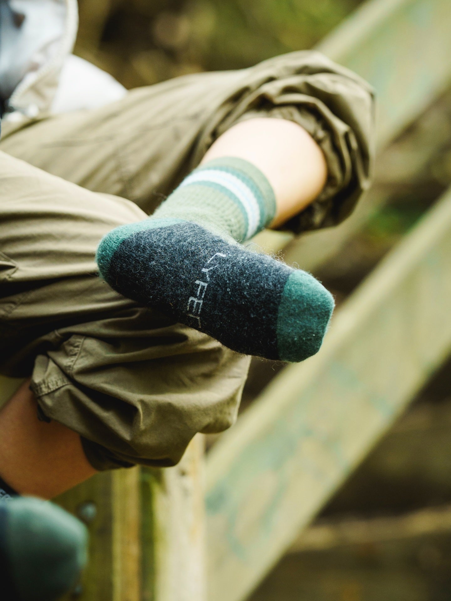 Model wearing Lyfer Original Field socks showing the LYFER weaved into the sole with a blurred natural background