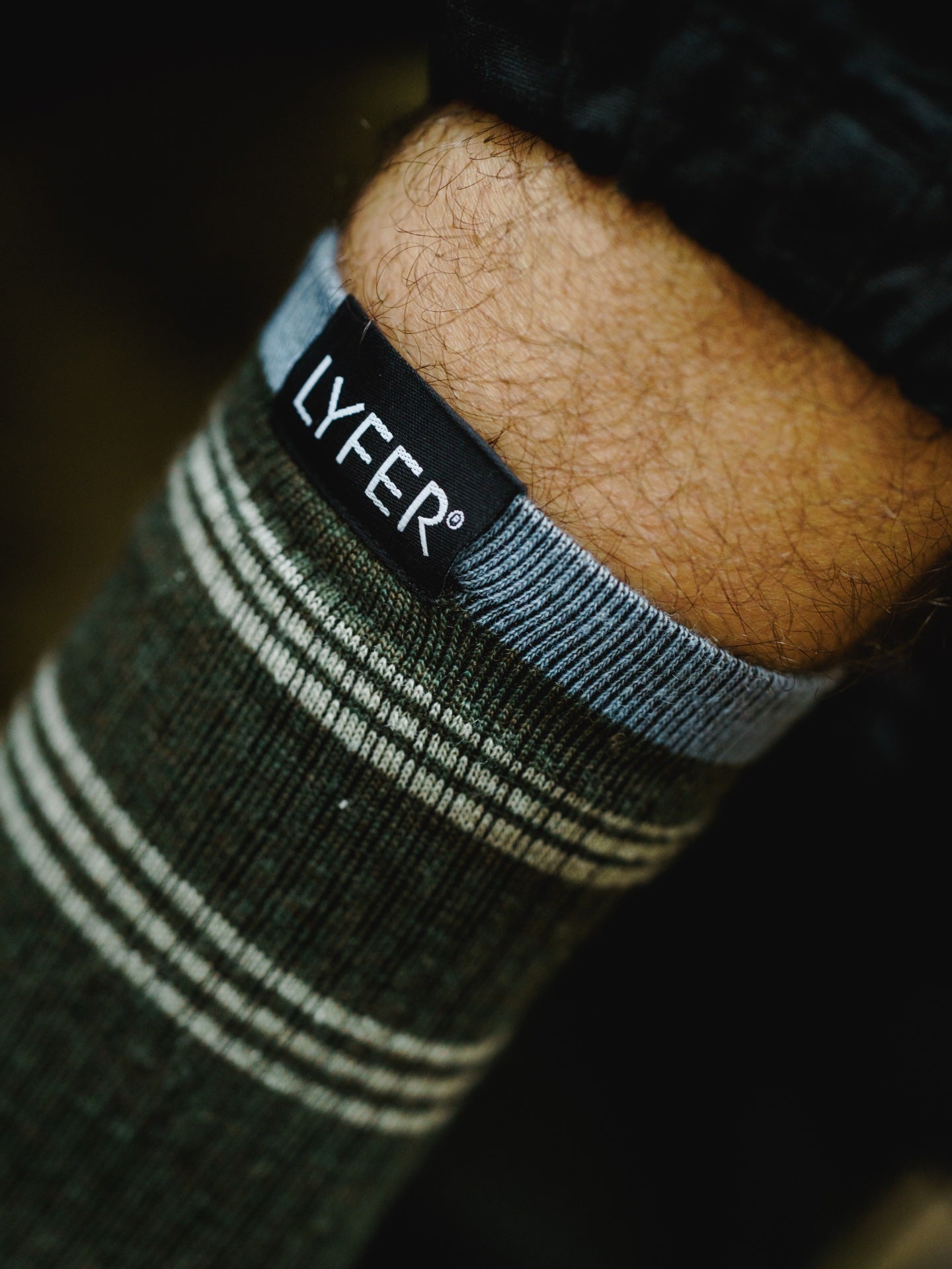 Close-up of a sock with 'LYFER' branding on a dark background, showing detail of sock manufacturing.