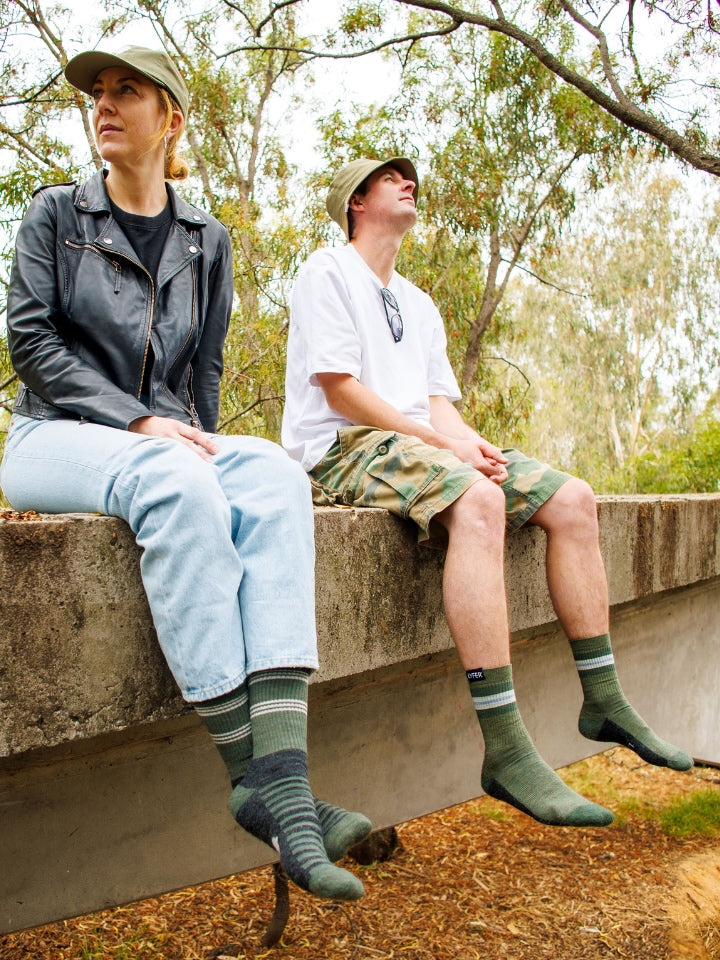 Image of 2 models sitting in nature looking out towards birds, wearing lyfer  Birdwatching socks, popular birdlover gift in Australia.