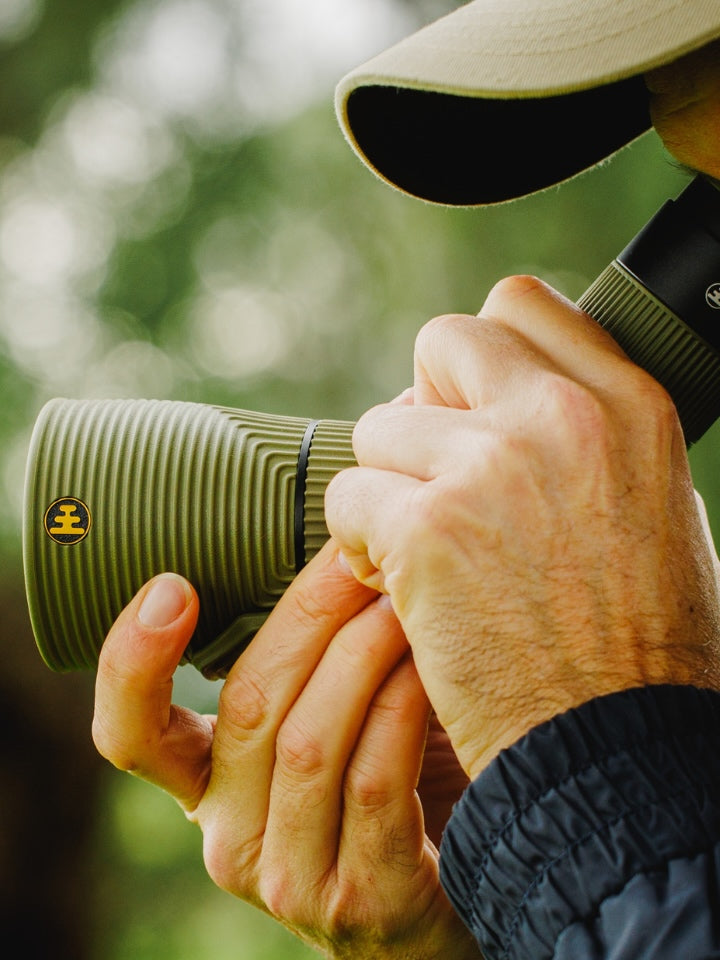 Person holding a green NOCS Scope Lite with a blurred natural background