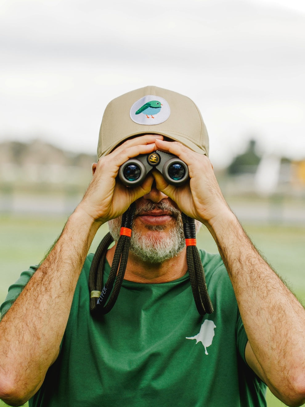Model outdoor with binoculars wearing the LYFER Patch Cap male bird