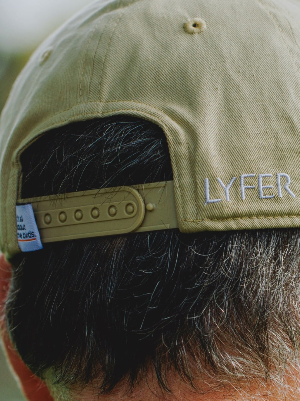 back of the LYFER cap showing the brand embroidery and the snapback with Its all about the birds woven tag
