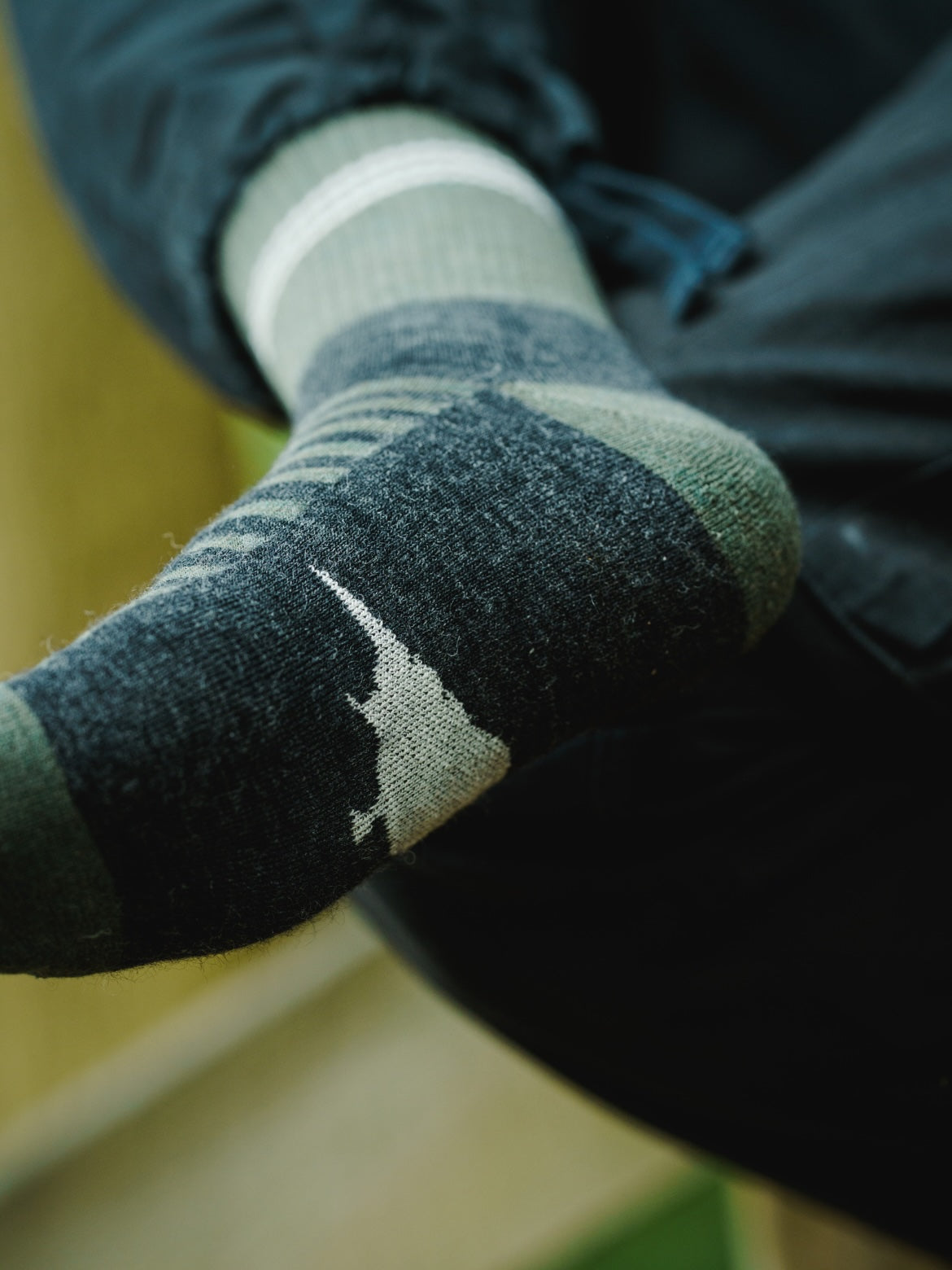 Close-up of LYFER field socks with a blurred background and birdmark logo on sole