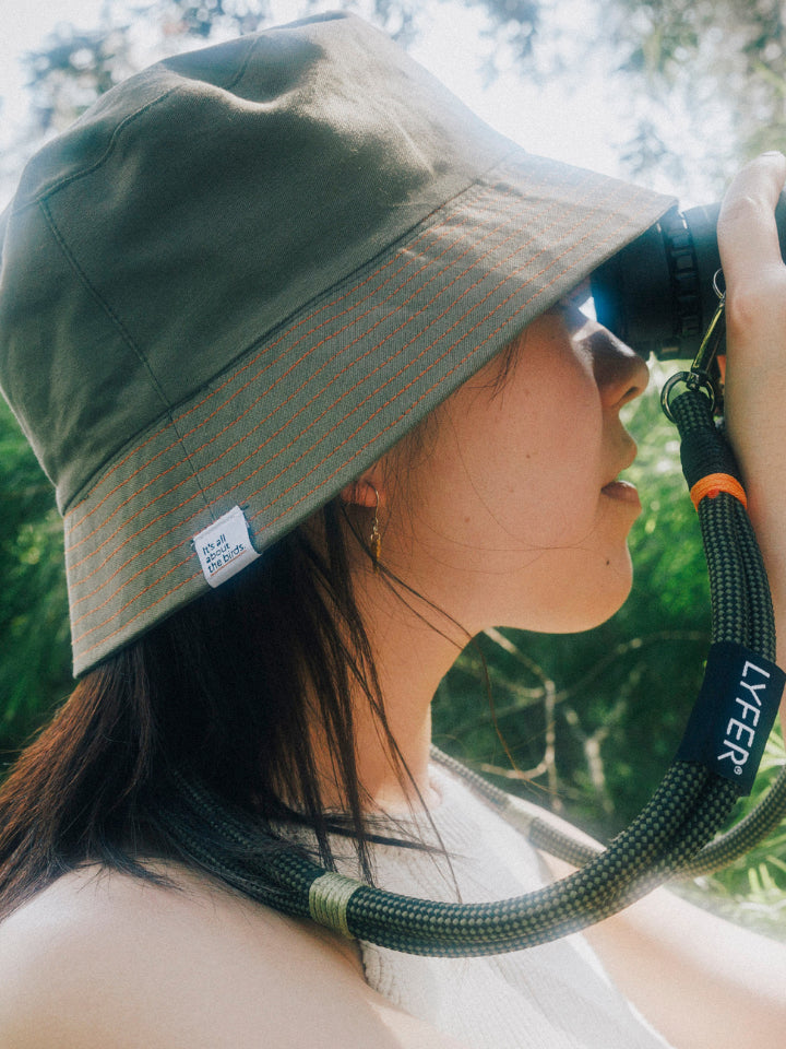 Model wearing Lyfer Green Bucket Hat while looking through binoculars