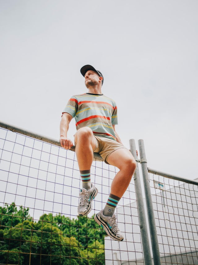 Model wearing the endangered range socks that are nature-inspired socks for the outdoors sitting on an urban fence.
