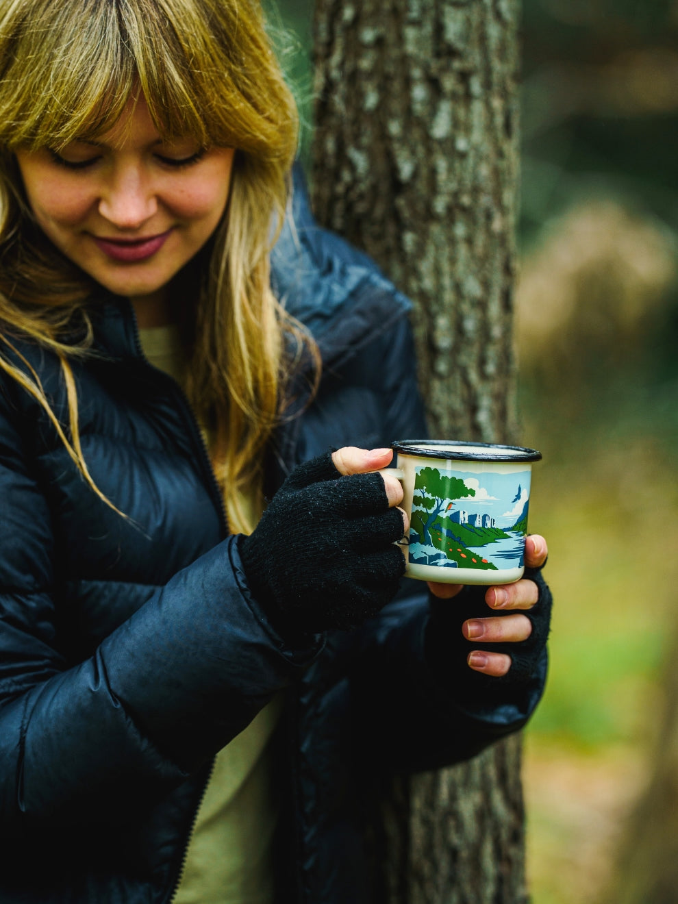 Image of model holding the Lyfer enamel mug with bird illustration