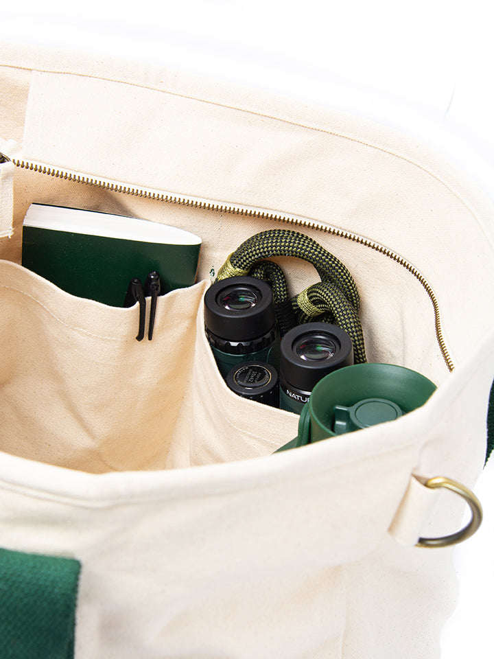 Close up the corner of the tote bag showing the compartments with birding accessories in the pockets. 