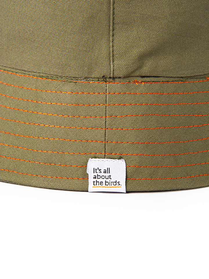 Close up shot of the orange thread stitching and the Its All About the Birds woven tag. This is a designer bucket hat for bird-lovers.