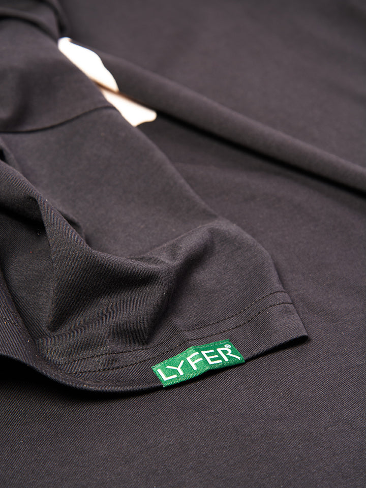 Close-up of Lyfer Birdmark T-shirt sleeve, displaying the woven fabric tag with the brand’s LYFER on it, this is a bird lover's t-shirt.