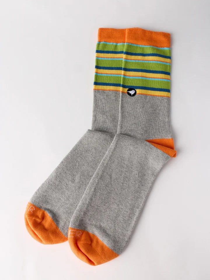 A pair of crew socks with a heather gray body, bright orange toes and heels, and a striped cuff featuring green, blue, yellow, and orange bands. A small black-and-white logo is visible on the side.