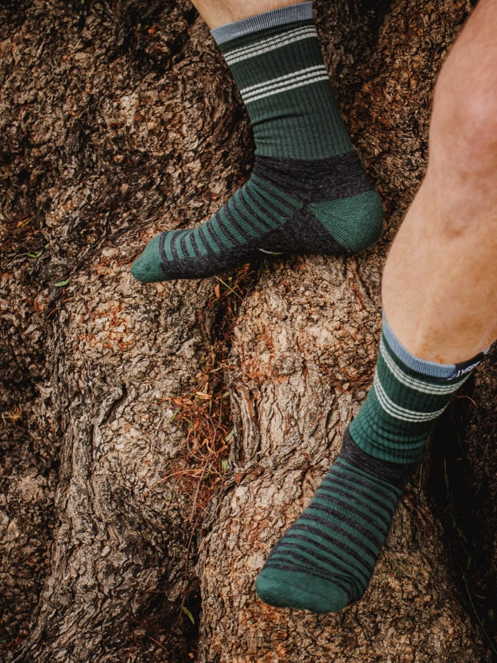 Person wearing LYFER Field socks on a tree trunk
