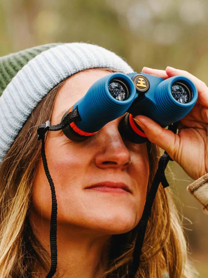Model holding NOCS binoculars wearing a LYFER beanie looking at birds