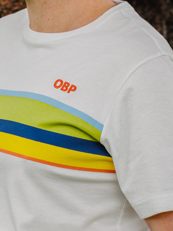 White t-shirt with colorful stripes and 'OBP' logo on a person wearing it.