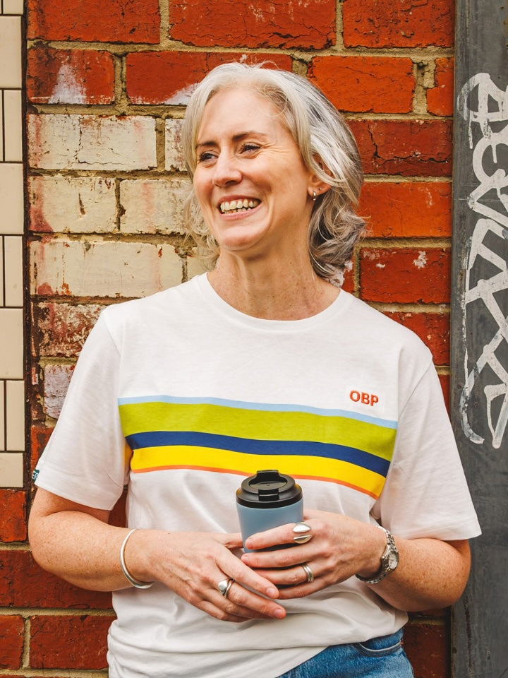 Model smilling and holding a coffee cup wearing the Orange Bellied Parrot Tshirt.