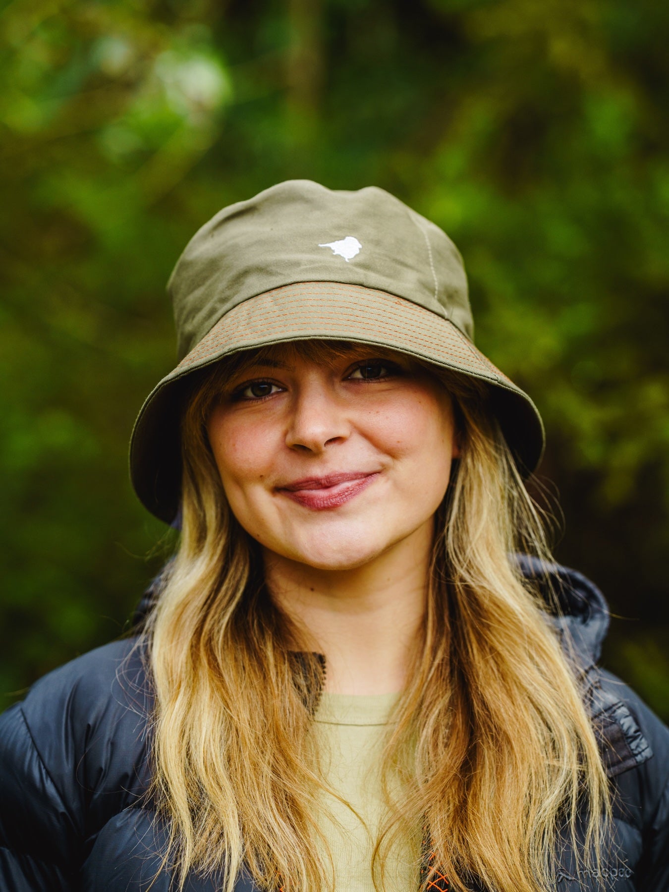 Model wearing the lyfer birdmark bucket hat our in nature birding.