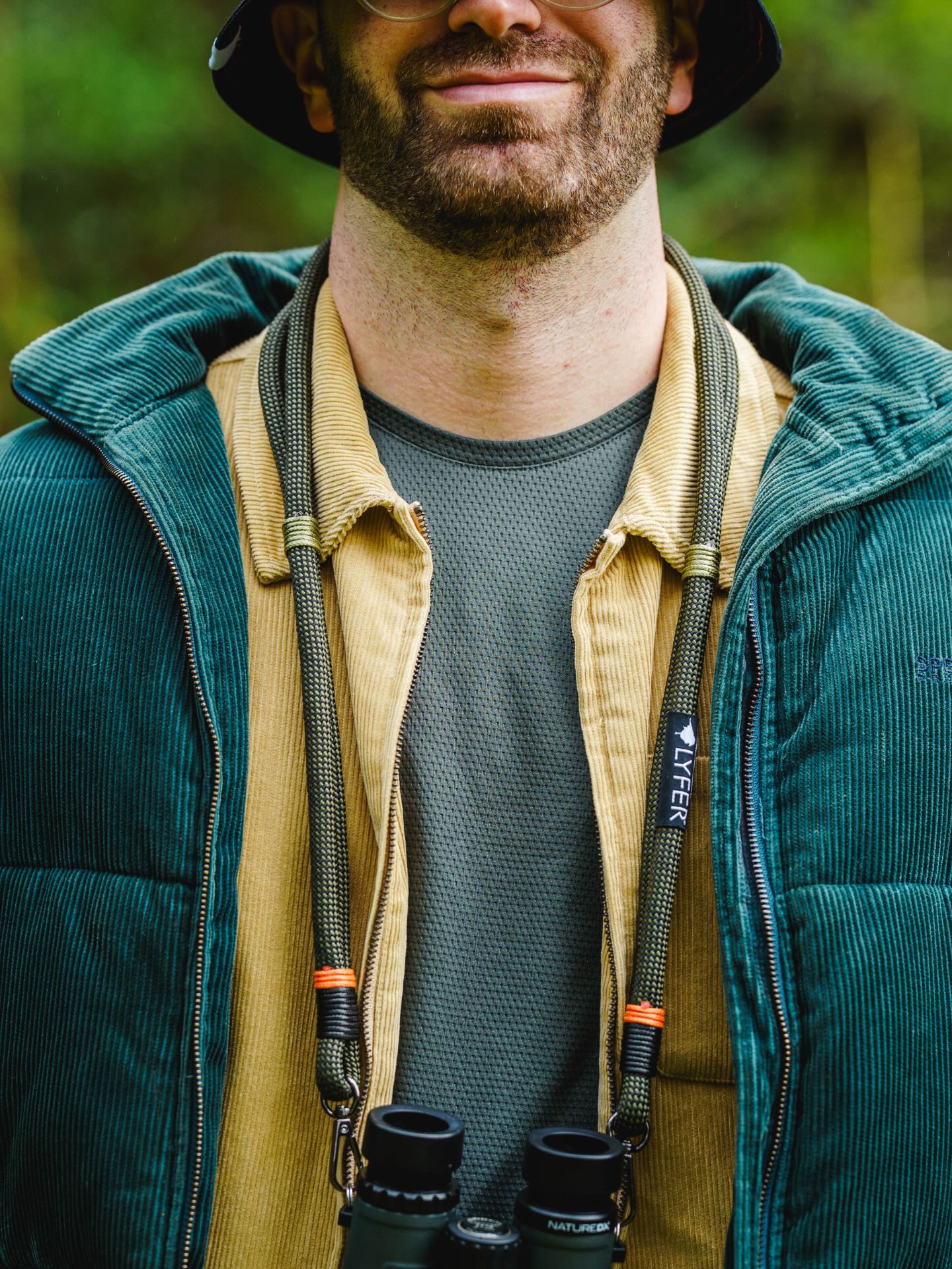 Model wearing Lyfer original binocular and camera straps out in nature while bird-watching.