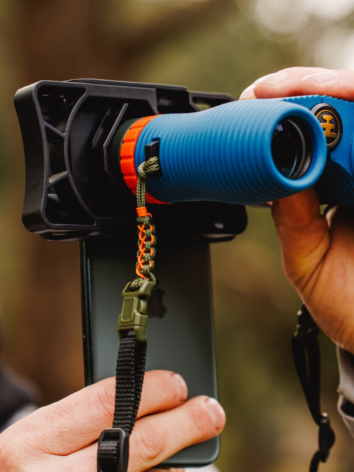 Close up of NOCS binoculars with LYFER adjustable straps, using the Rig Adaptor with a model holding it in their hand