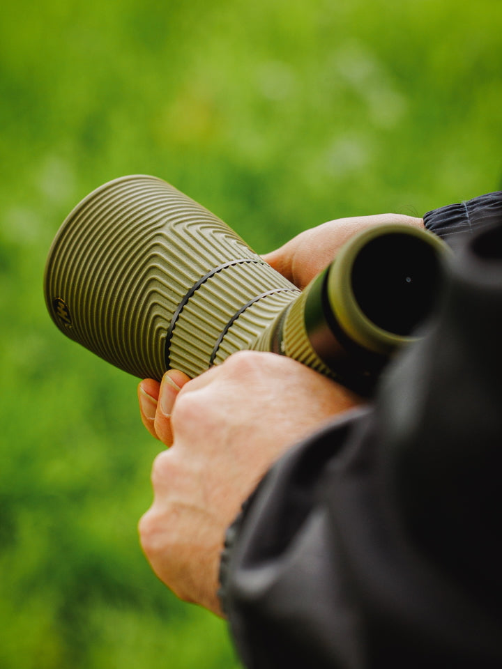 Person holding a green NOCS Scope Lite against a blurred green background
