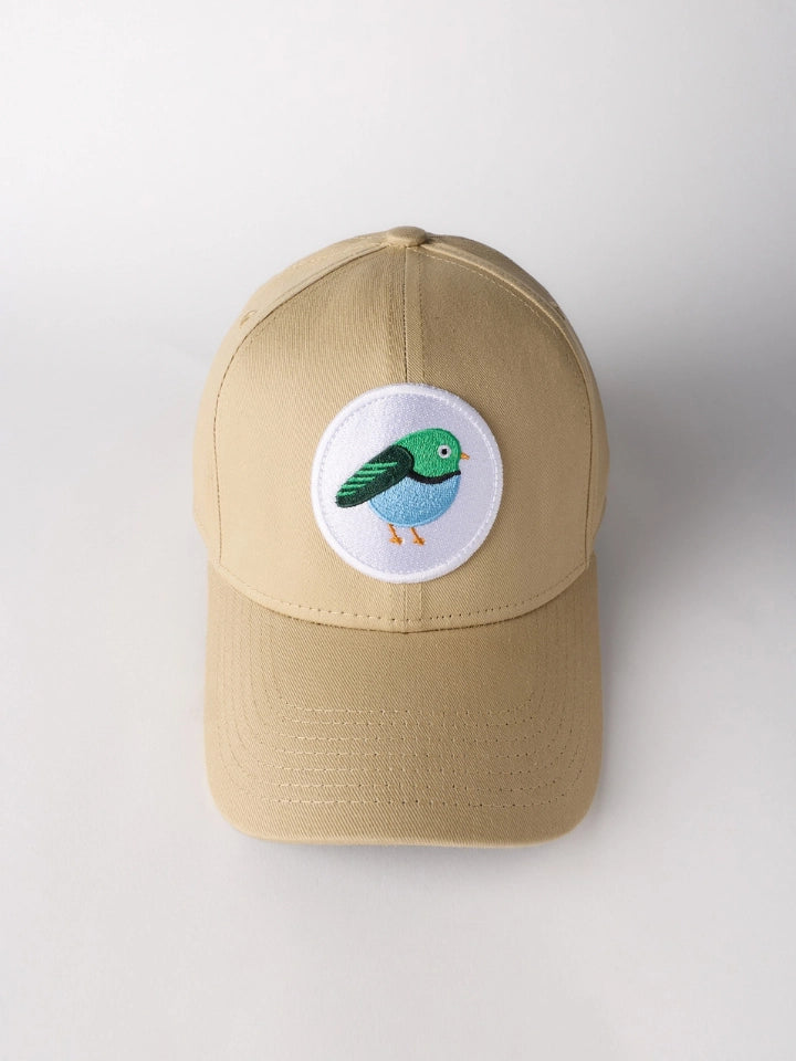 A beige baseball cap featuring a circular white patch on the front with an embroidered bird in green, blue, and orange, set against a plain light gray background.