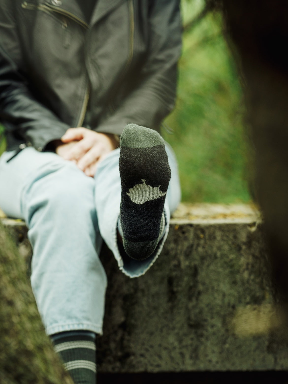 Person wearing LYFER Field socks with a birdmark design
, sitting outdoors.